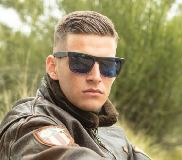 Man wearing sunglasses and a leather jacket outdoors.